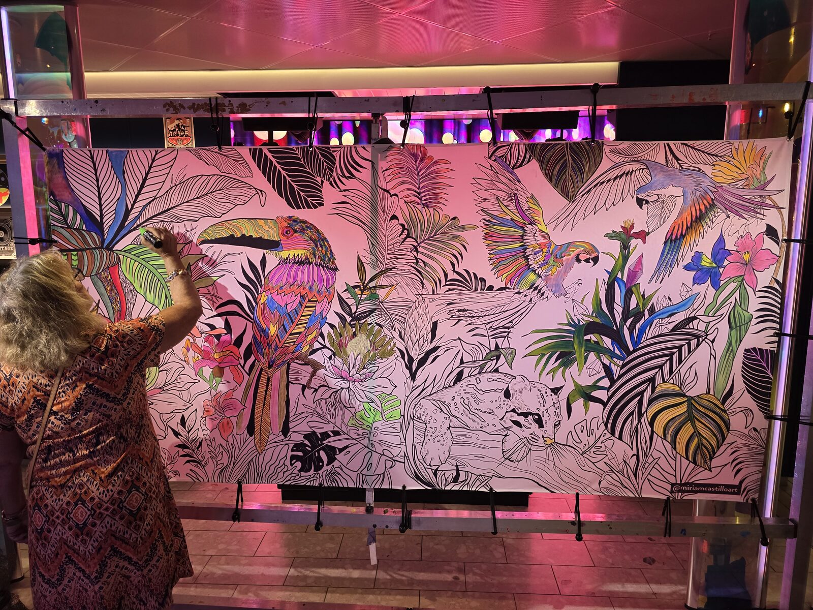 A guest coloring in a communal mural alongside fellow sailors on Virgin Voyages